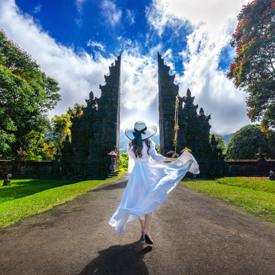 Woman walking at big entrance gate, Bali in Indonesia.