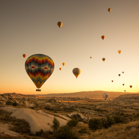A set of colored balloons flying above the ground in Cappadocia, Turkey
